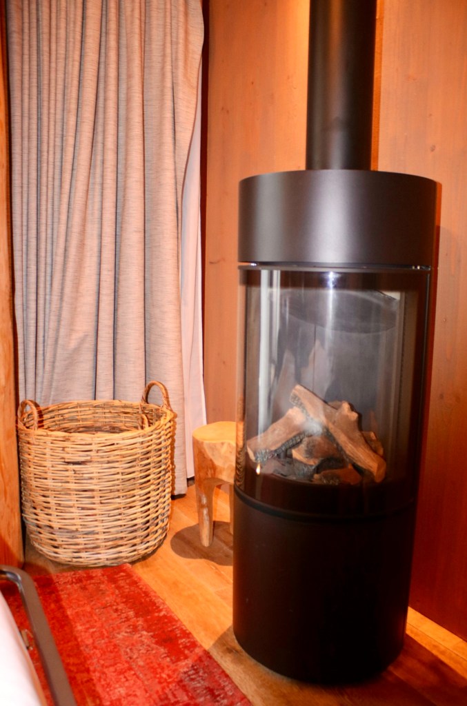 Things Helen Loves, black round wood burning stove with log basket next to it in Pairi Daiza lodge, Belgium